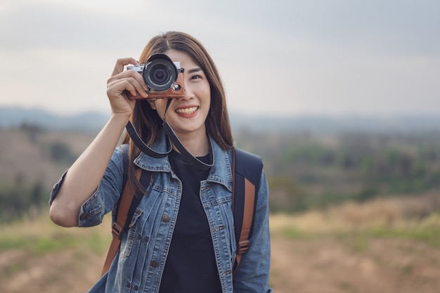 Tourist woman taking photo with her camera in nature