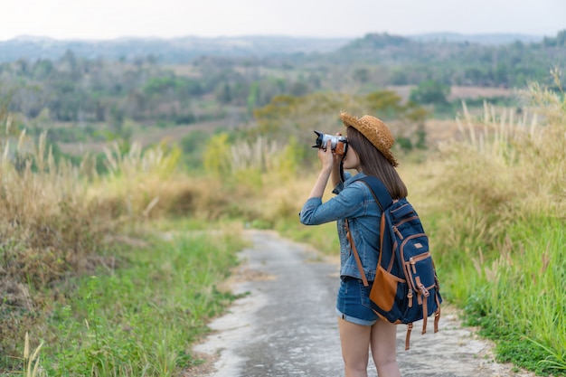 Tourist woman taking photo with her camera in nature