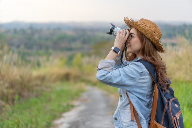 Tourist woman taking photo with her camera in nature