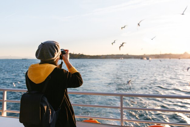 Tourist woman taking travel picture with camera of Bosphorus Strait during autumn holidays