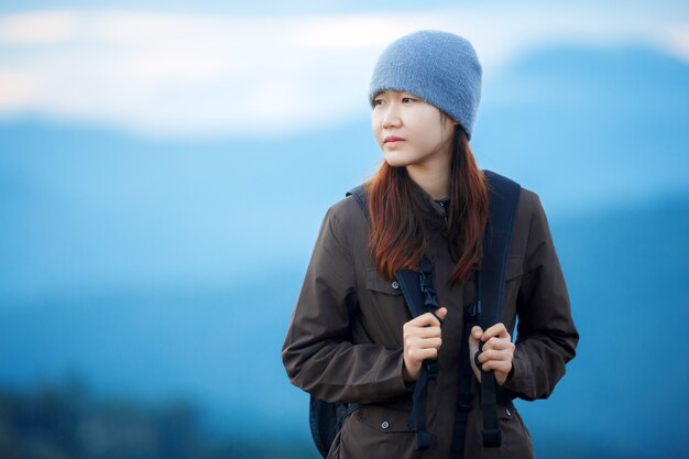 tourist woman with backpack on blue mountains background