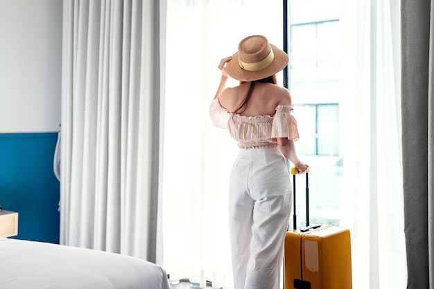 Tourist woman with luggage in hotel after check-in