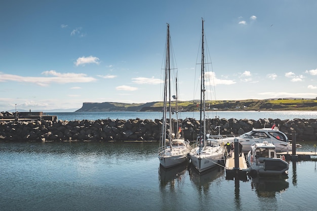 Touristic yachts boat next to the small pier and stone fence northern ireland comfortable vehicles