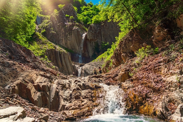 Tourists on beautiful waterfall in the mountains