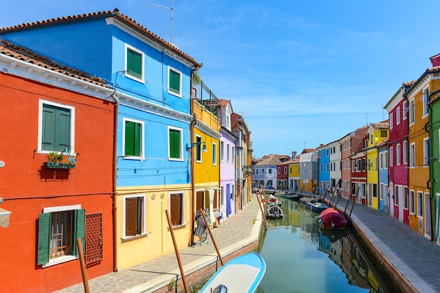 Tourists among the sovereign shops and restaurants on the main street of burano Island Colorful houses on the canal Venice Italy