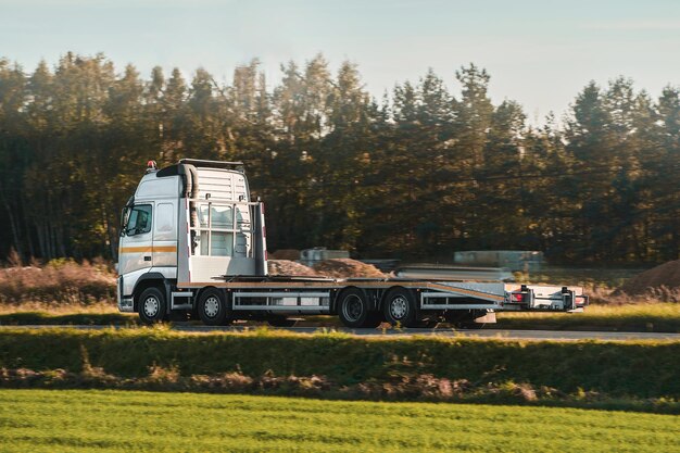 A tow truck carries a broken car on the highway in bad weather Roadside assistance helps a driver in trouble Rollback tow truck