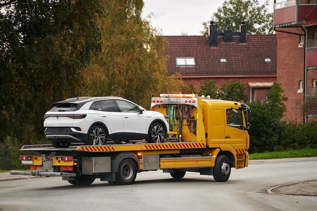 Photo a tow truck carries a car on a flatbed trailer on the highway providing transport service and assistance after an accident