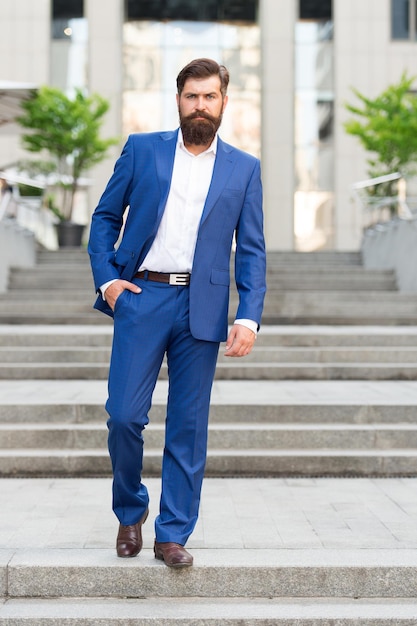 Toward business achievements. Conquer business world. Office worker confidently step on stairs. Bearded man going to work. Business man in modern city. Beginning of working day. Motivated for success.