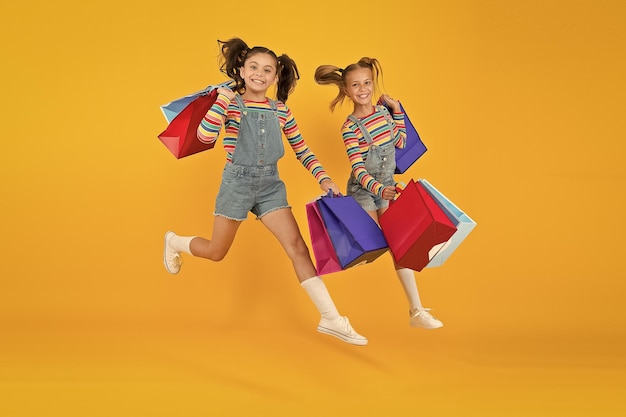 Towards purchase Modern fashion Kids fashion Cute children hurry up for sale season Discount and sale Little girls carry shopping bags Matching outfits Trendy and fancy Fashion shop