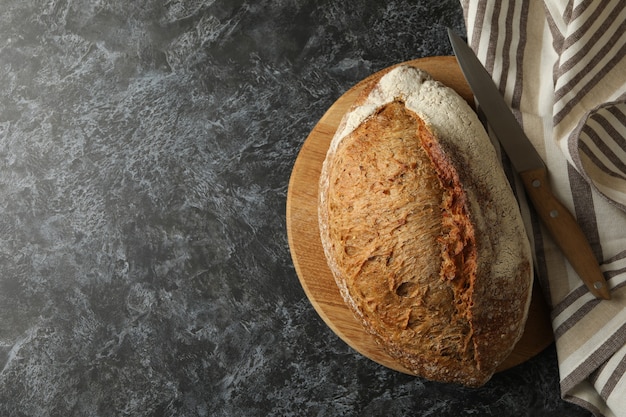 Towel, board with bread and knife on black smokey