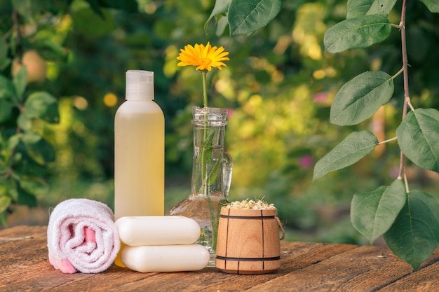 Towel, soap and plastic bottle with marigold extract and bowl with dry flowers of chamomile.