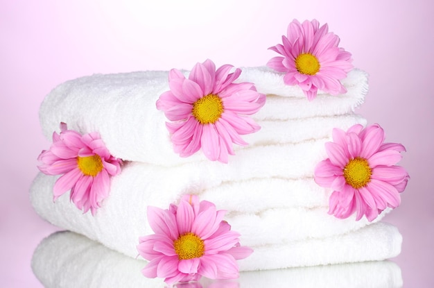 Towels and beautiful flowers on pink background