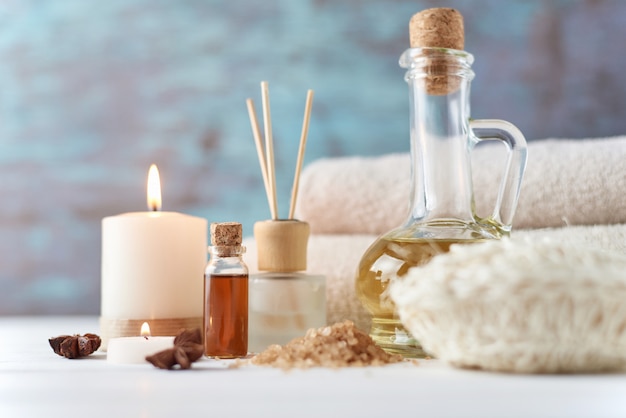 Towels, candle and massage oil on white table