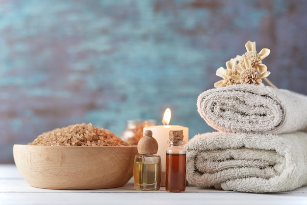 Towels, candle and massage oil on white table