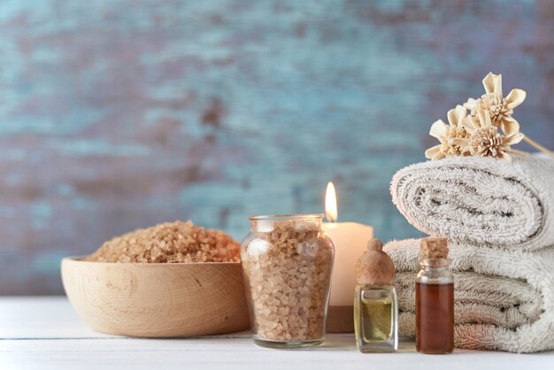 Towels, candle and massage oil on white table