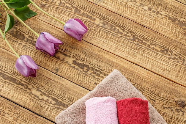 Towels and lilac tulip flowers on wooden background