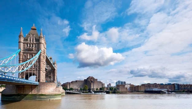 Tower Bridge on a bright sunny day with blue sky and clouds Calm water with reflections London England UK