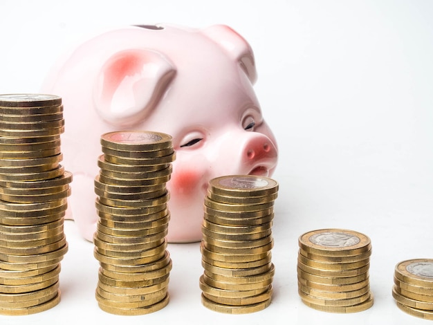 Tower of coins isolated on white background with pink pig studio shot