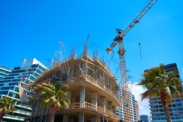 Tower crane on the construction site of a modern building near the sea