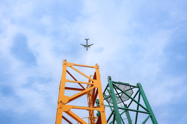 Photo tower crane in at construction site with air plane on sky in the background