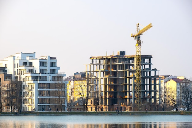 Tower crane and high residential apartment buildings under construction on lake shore Real estate development