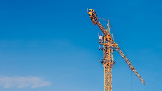 Tower Crane lattice boom hook clear blue sky sun background Construction site work building installation