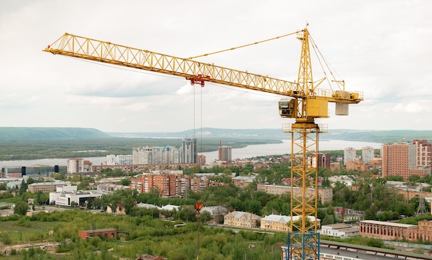 Tower crane top view building background river sunset mountains concept construction new buildings architecture and industry construction big city against backdrop city mountains