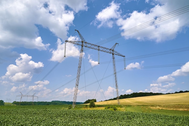 Tower with electric power lines for transfering high voltage electricity located in agricultural cornfield. Delivery of electrical energy concept