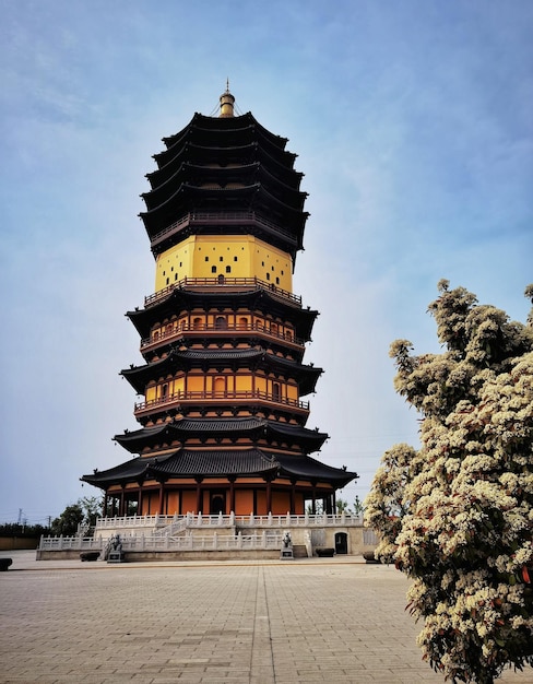 A tower with a yellow roof and a tree in the foreground