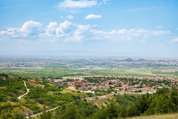 Town Plovdiv with houses and fields against backdrop of Rhodope Mountains and hills covered with forests and cloudy sky