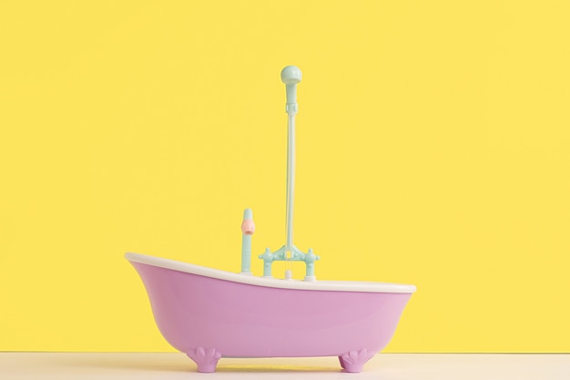 Toy bathroom with shower for doll on yellow wall. Infant washing and bathing. Hygiene and care of young children.