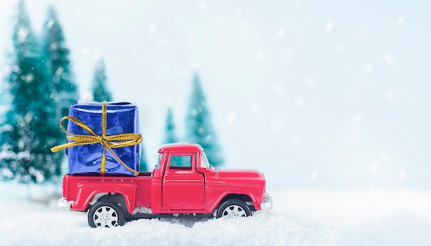 Toy car carrying a gift in the winter forest