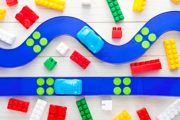 Toy car plastic road and colorful blocks on white wooden background top view