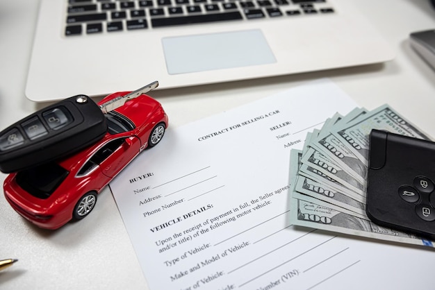 Toy car with key dollar and laptop document for buy or rent auto at office desk