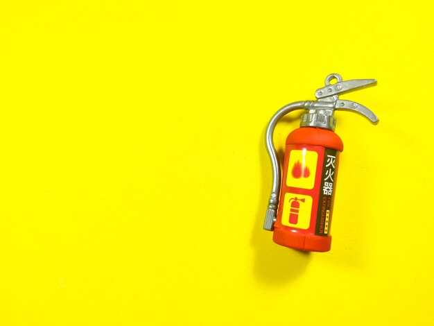 Toy fire extinguisher on a yellow background with copy space