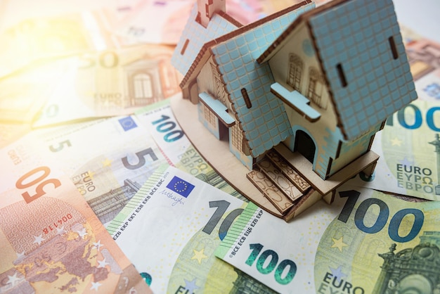 Toy house with a roof on euro banknotes as background