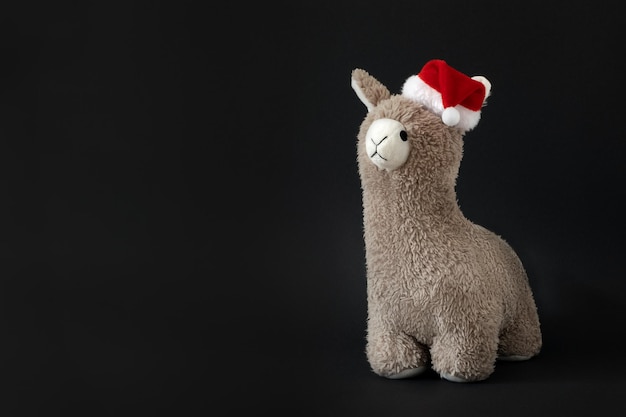 Photo toy lama in christmas santa hat black background