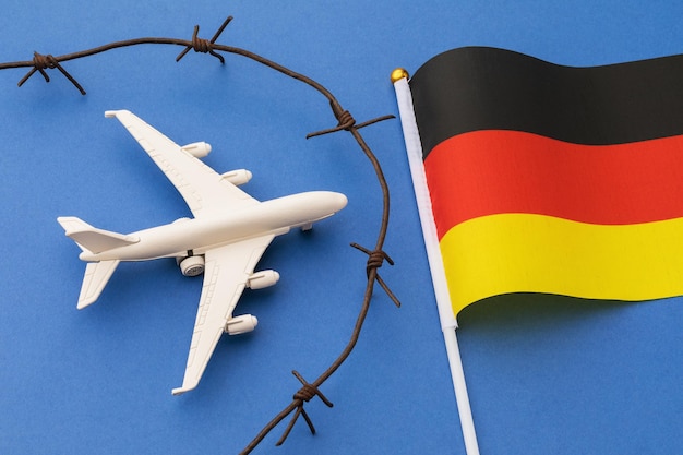 Toy plane, Germany flag and barbed wire on blue background, country air border security concept