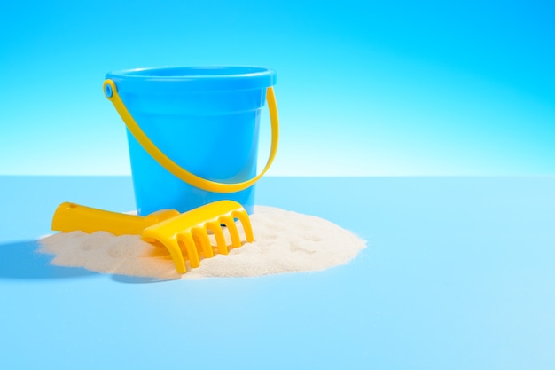 Toy plastic pail and a rake on the sand