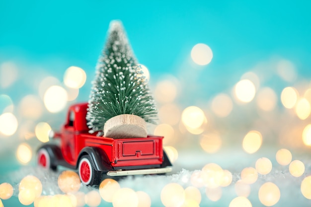 Toy red car with a Christmas tree on the roof on a bokeh festive blue background. Christmas and New Year concept