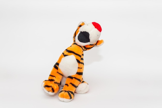 Toy striped cute tiger a symbol of the New year soft orange toy tiger on a white isolated backgroundCopy space closeup selective focus The concept of welcome to 2022