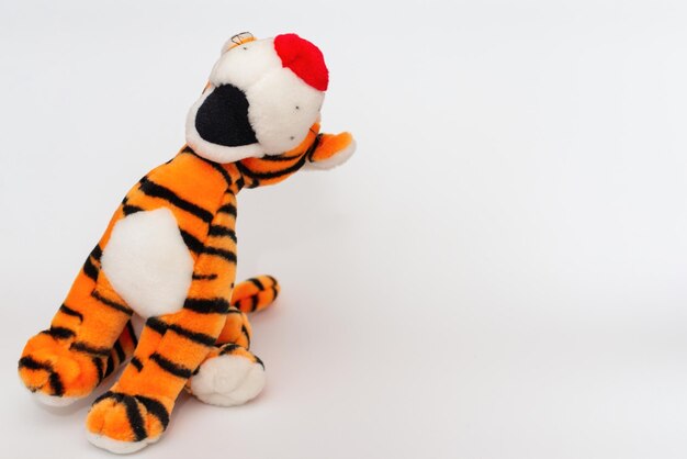 Toy striped cute tiger a symbol of the New year soft orange toy tiger on a white isolated backgroundCopy space closeup selective focus The concept of welcome to 2022