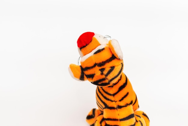 Toy striped cute tiger a symbol of the New year soft orange toy tiger on a white isolated backgroundCopy space closeup selective focus The concept of welcome to 2022Back view