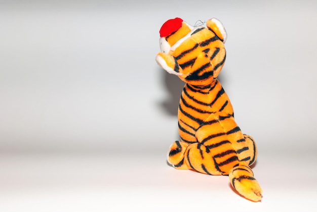 Toy striped cute tiger a symbol of the New year soft orange toy tiger on a white isolated backgroundCopy space closeup selective focus The concept of welcome to 2022Back view