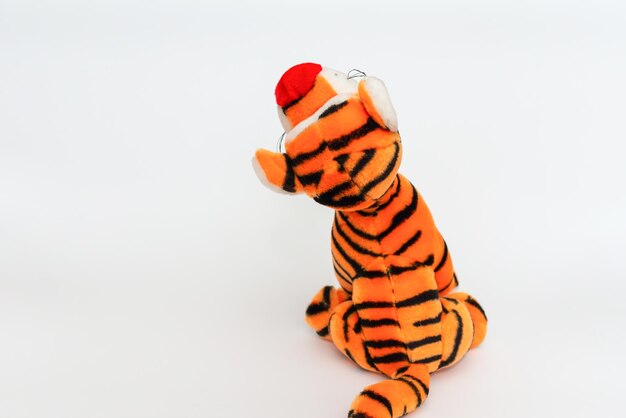 Toy striped cute tiger a symbol of the New year soft orange toy tiger on a white isolated backgroundCopy space closeup selective focus The concept of welcome to 2022Back view