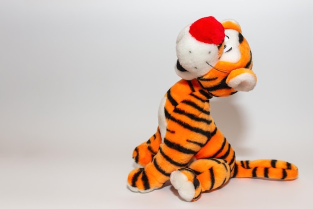 Toy striped cute tiger a symbol of the New year soft orange toy tiger on a white isolated backgroundCopy space closeup selective focus The concept of welcome to 2022Side view