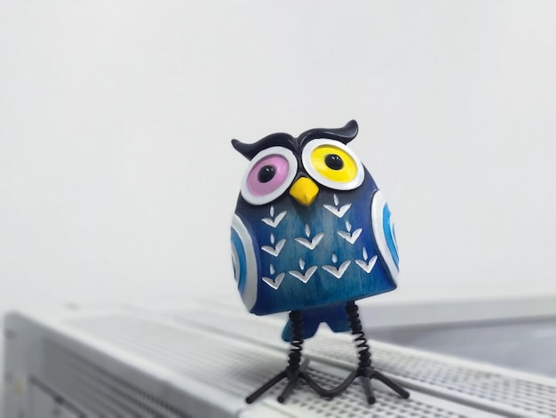 Photo a toy of a surprised blue owl with multicolored eyes closeup stands on a white background