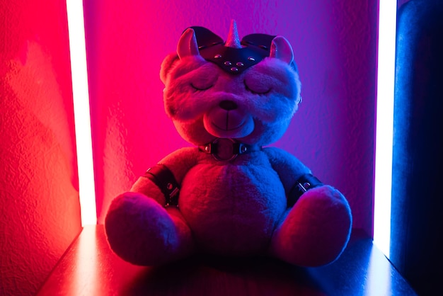 A toy teddy bear dressed in leather straps and a mask an accessory for BDSM games in a sleep mask