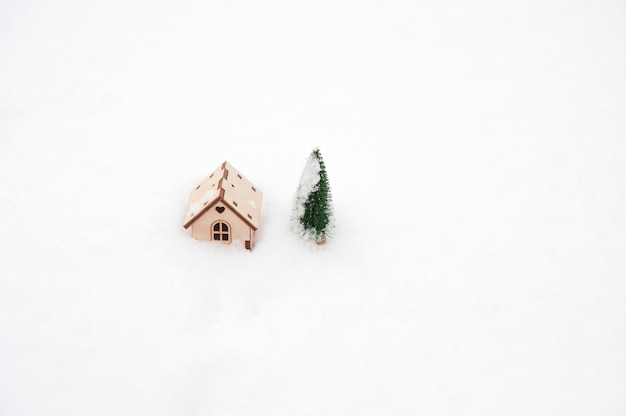 Toy wooden house and christmas tree in the snow