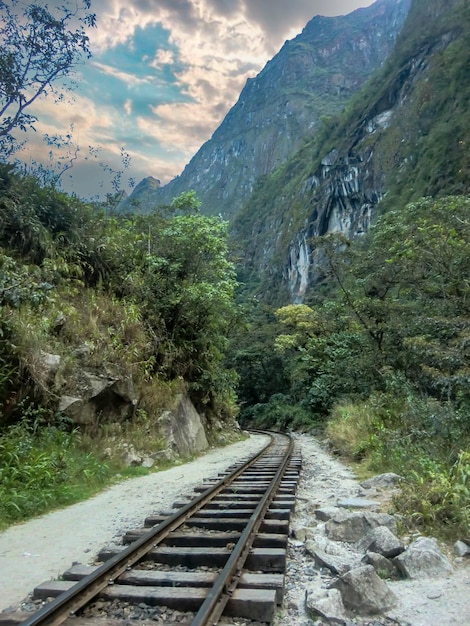 Track of a train around a jungle in Cusco - Peru, in the background a waterfall